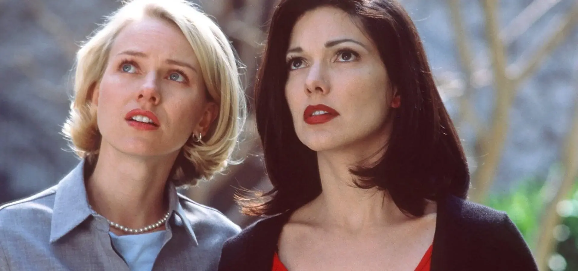 A blonde woman and a brunette are staring at something, looking vaguely scared