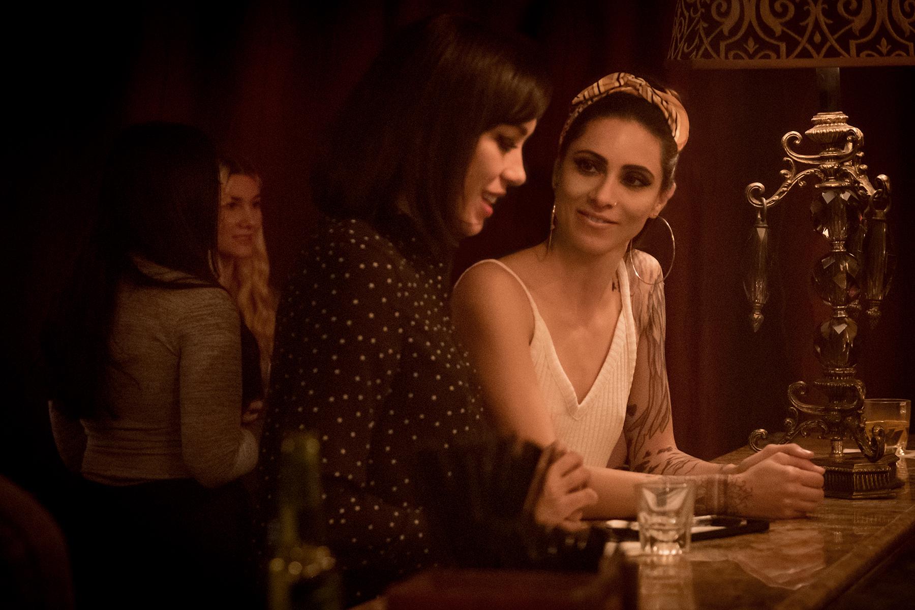 Two women are talking with each other at a bar